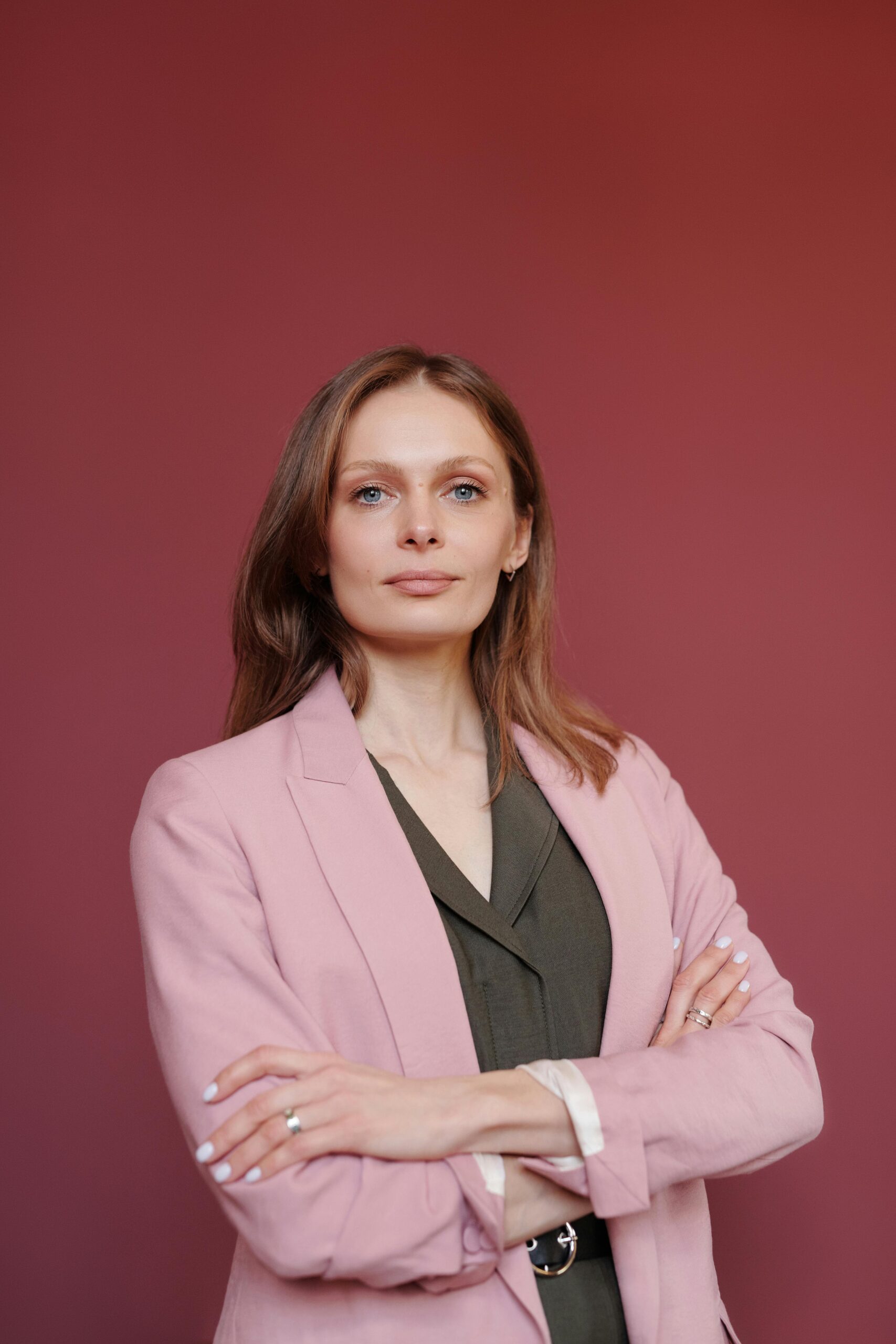 Elegant businesswoman with arms crossed in studio portrait, showcasing leadership and confidence.